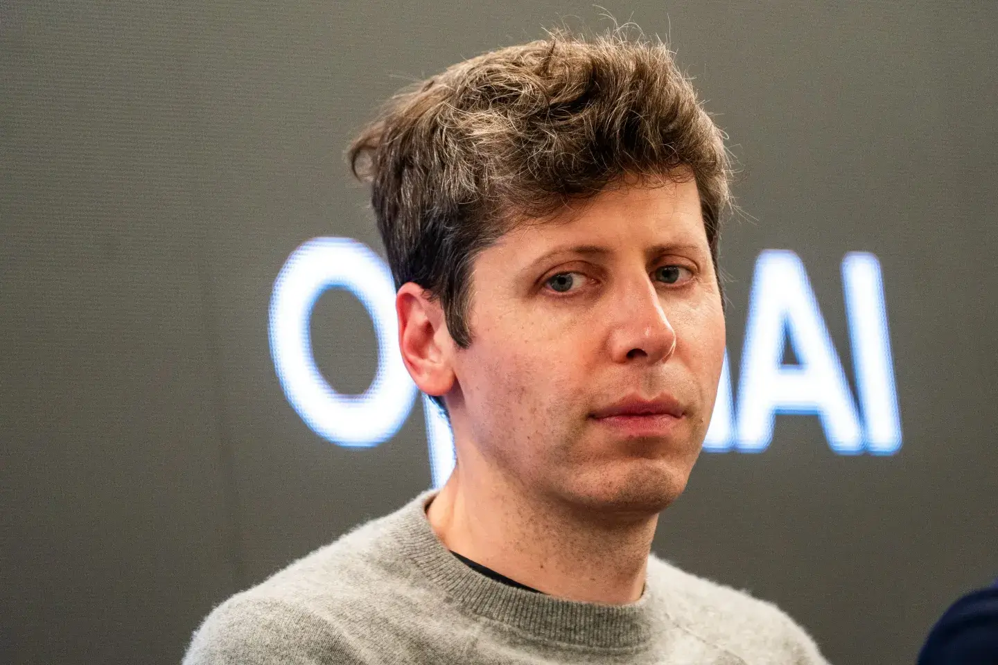 Sam Altman, administrerende direktør i OpenAI, foran OpenAI-logo
